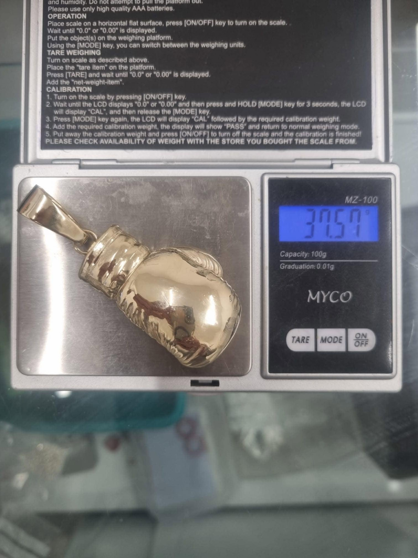 Heavy polished gold boxing glove pendant on the scales