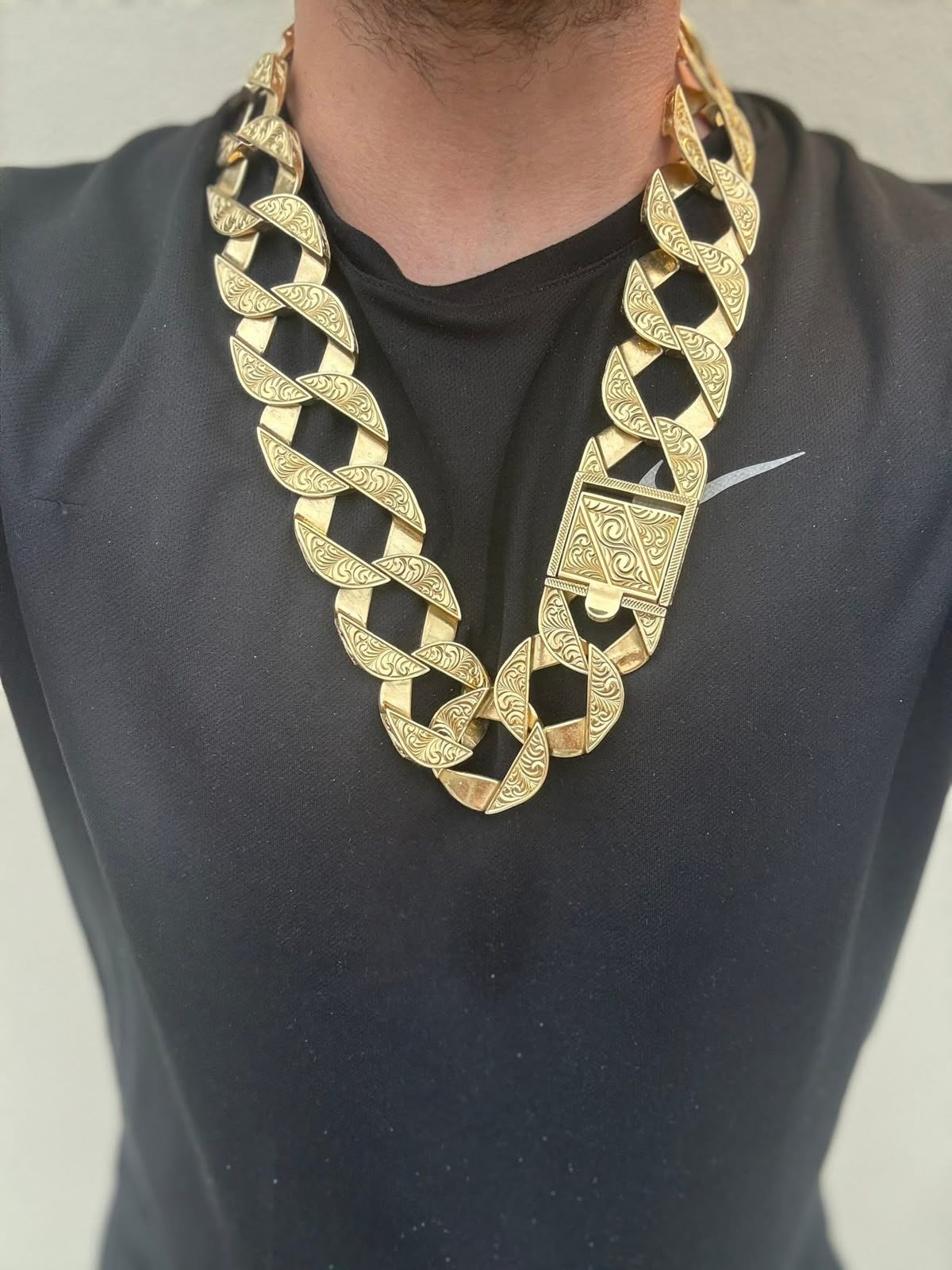 Wide gold statement necklace with engraved links and a decorative lock