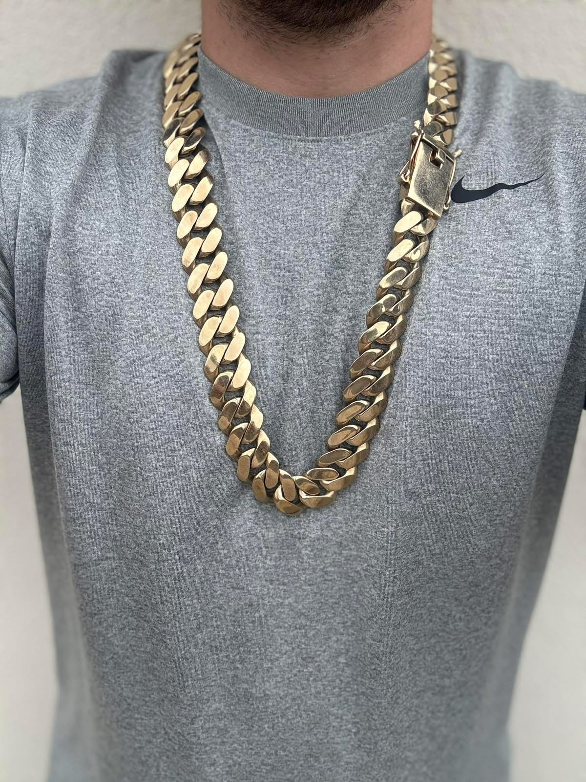 Classic heavy gold curb necklace worn over a grey top