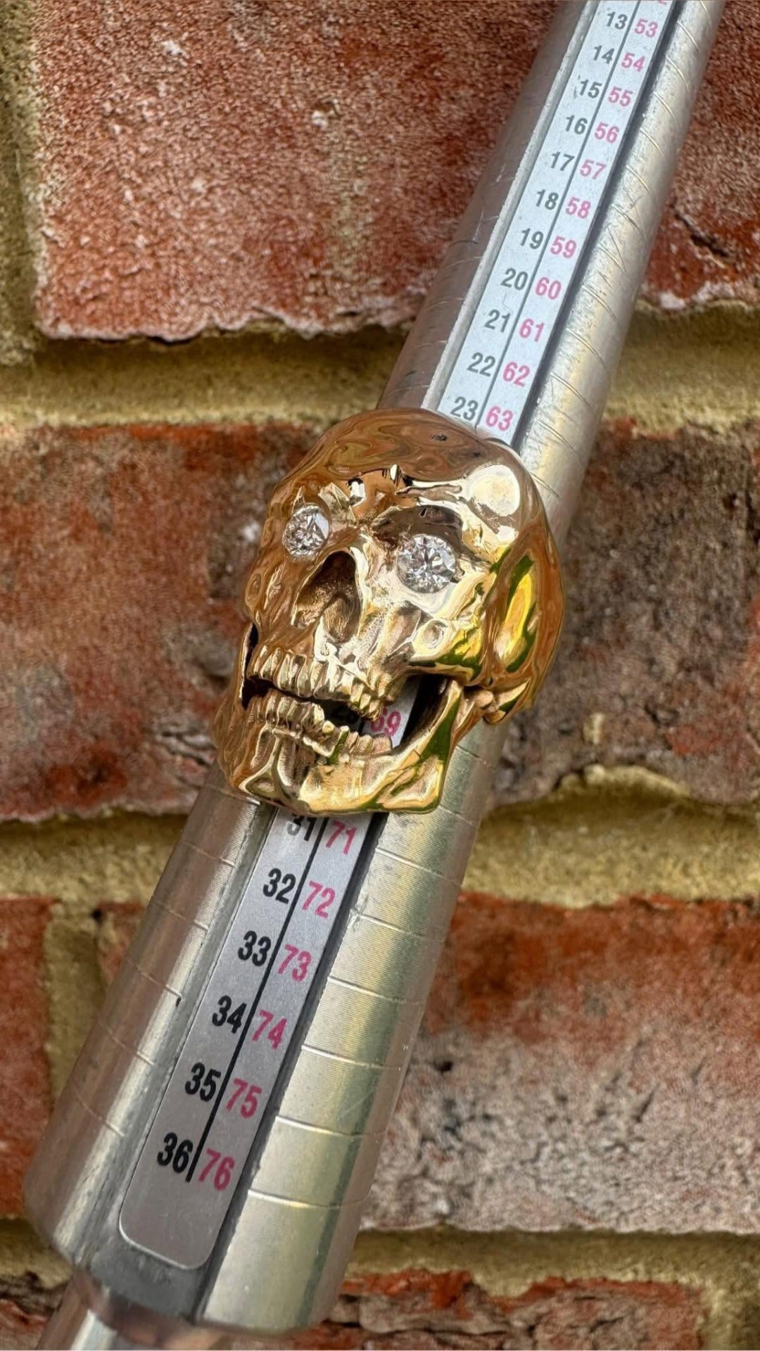 Gold skull ring with diamond-set eyes on a ring sizer
